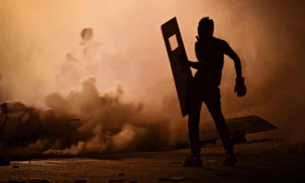 A Bahraini protester is surrounded by tear gas fired by riot police during clashes in July 2013