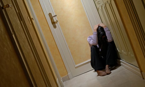Depressed woman sitting in corridor with head in hands