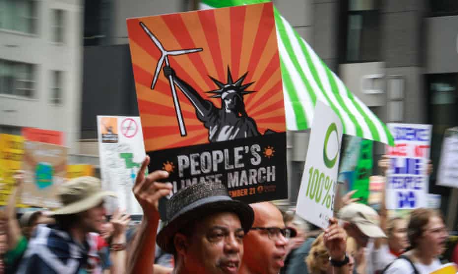 man holding people's climate march sign