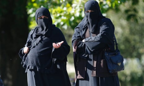 Two women wearing full-face veils walk in Regents Park in London.