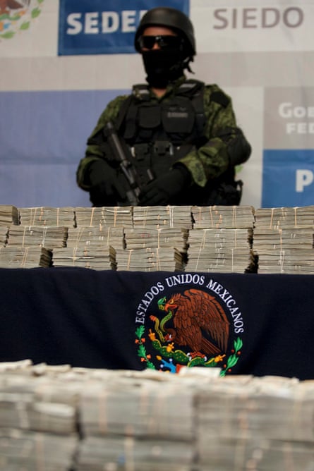 A Mexican soldier guarding $15m seized in an operation in Tijuana.
