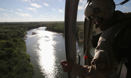 A helicopter crew member from the US Office of Air and Marine flies over the Rio Grande. The helicopters patrol day and night searching for drug and people smugglers.