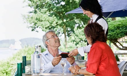 Waitress bringing the bill to the table at an outdoor terrace restaurant