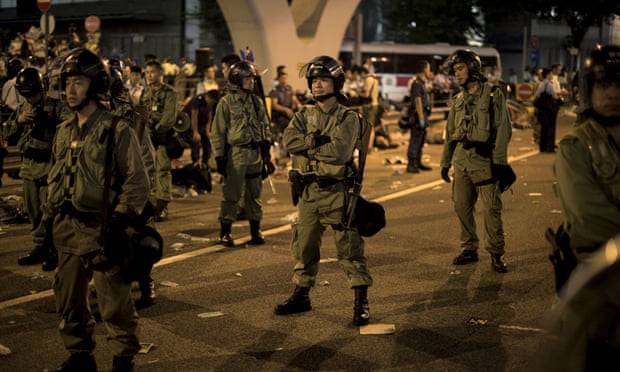 Police officers hold their ground surrounded by pro-democracy protesters on a major road in the heart of Hong Kong.