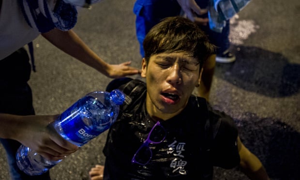A pro-democracy demonstrator pours water over a man's face after police fired teargas at protesters in Hong Kong.