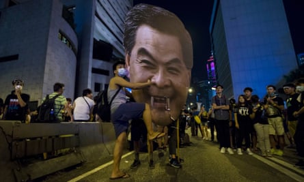 A protester hits a cutout of Hong Kong chief executive Leung Chun-ying, which had been given fangs.