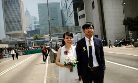 Newly married couple Vivian Lo and Ka Sing Fung, both 30 years old from Hong Kong, pose for their personal photographer, in front of the protest site of pro-democracy activists.