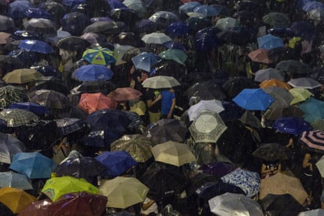 Pro-democracy protestors use umbrellas to shield themselves from heavy rain in Hong Kong on September 30, 2014.