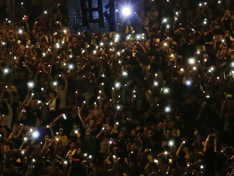 Protesters chant "Jiayou! Jiayou!"   or "Keep it up!"   while waving their cellphones with the LED flashlights sparkling in the dark as they gather on the streets near the government headquarters, Wednesday, Oct. 1, 2014 in Hong Kong.