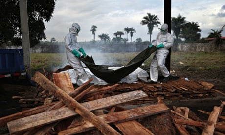 A burial team puts bodies of Ebola victims on to a funeral pyre in Marshall, Liberia.