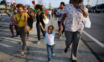 A girl holds a rose as she marches in Ferguson, Missouri