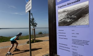 A young woman on rollerblades skates past an explanatory sign that shows what adjacent Baerwalder See lake once looked like on August 21, 2010 near Boxberg.