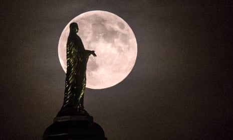 The full moon silhouettes the statue of the Virgin Mary on top the University of Notre Dame's golden dome in South Bend, Indiana, US.