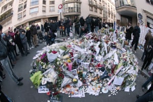 People lay flowers and candles close to offices of Charlie Hebdo in Paris