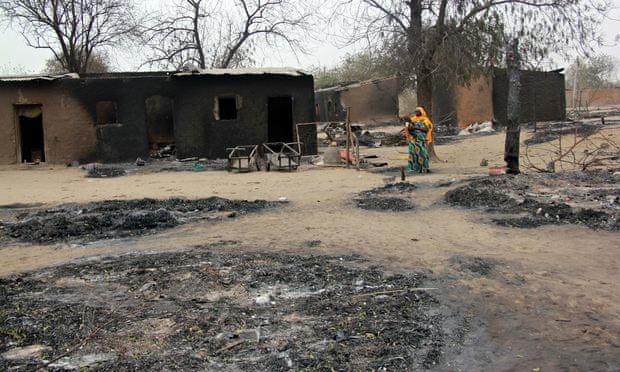 A 2013 photo shows a woman walking past burnt houses in Baga