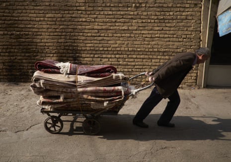 A worker pulls a cart stacked with handwoven Persian carpets at Tehran's carpet bazaar.