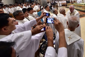 Priests take pictures of Pope Francis during the mass