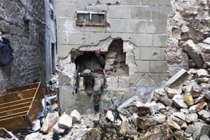 A Free Syrian Army fighter climbs out of a hole in a wall, on the old Aleppo frontline. A Pentagon spokesman said the US military is planning to deploy more than 400 troops to help train Syrian rebels to fight Isis.