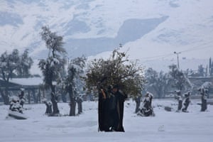A Syrian man carries wood for a fire in the rebel-held city of Douma. Three small girls and an elderly man died in Syria during the week due to bitterly cold temperatures and a week-long storm.