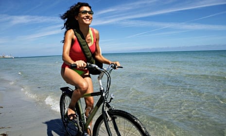 A young woman cycling on a beach, smiling