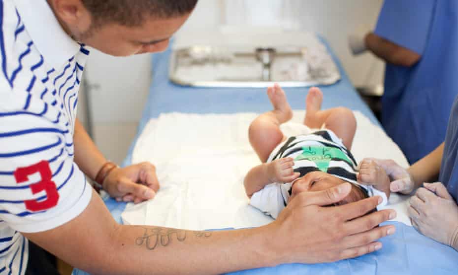 A father comforts his infant son before the child’s circumcision.