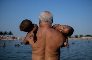 Rio de Janeiro, Brazil A man holds twins at the Ramos Pool on the day of St. Sebastian, the patron saint of the city