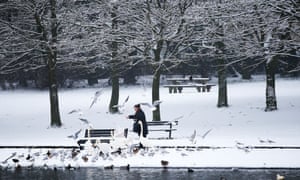 Yorkshire, UK A woman feeds the birds in Tarnfield Park, Yeadon, Leeds as the snow falls and the cold snap continues around the UK