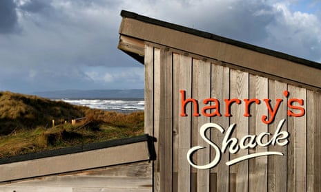 The wooden shed-like Harry's Shack with the sea behind and a stormy sky
