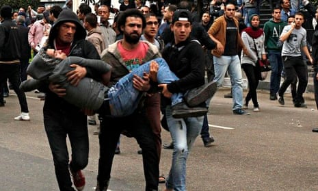 Anti-government protesters help an injured protester wounded during violent scenes in front of the p