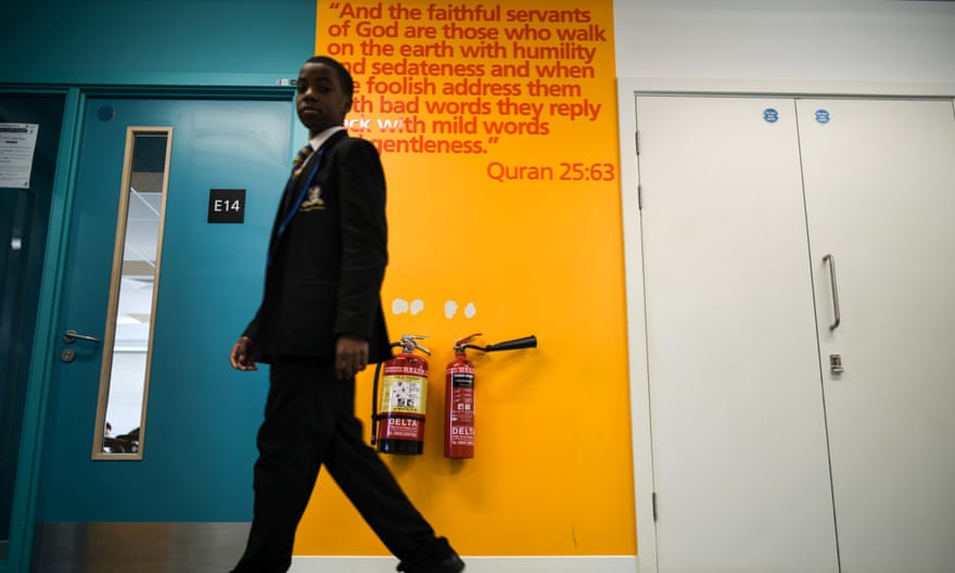 A pupil walks past an excerpt from the Qur’an, with more daubed on walls throughout the school.