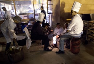 Kitchen workers gather around a fire outside the Rashtrapati Bhavan, the presidential palace, during the State Dinner