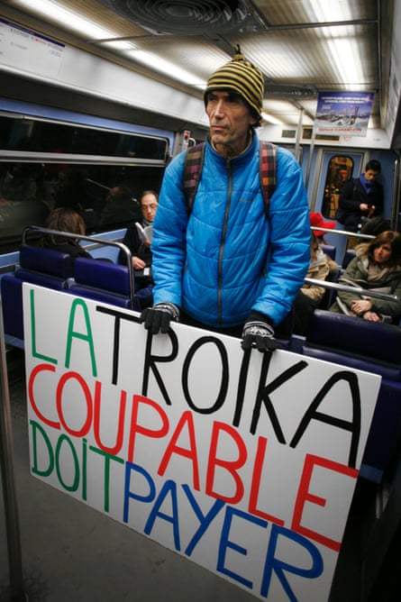 The French political activist Voltuan going to a Syriza party gathering, holding a placard reading: 'The guilty Troika must pay'.