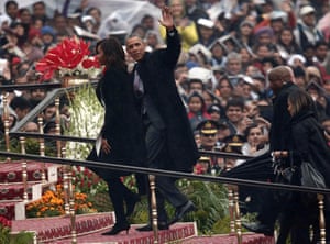 President Obama waves as he and first lady Michelle Obama arrive in the rain to attend the Republic Day parade