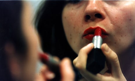woman applying lipstick in front of mirror