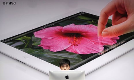 An employee sits in front of a poster advertising the New iPad at an Apple dealership in Wuhan, Hubei province, China.