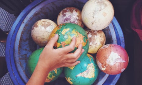 Hand of a child reaching for a small world globe