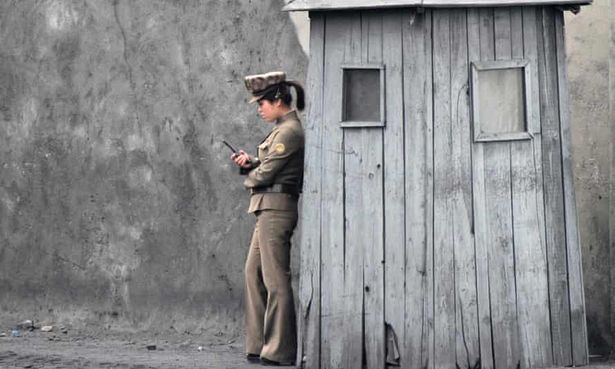 A North Korean soldier uses her mobile phone next to a sentry on the banks of the Yalu River, near the North Korean town of Sinuiju, opposite the Chinese border city of Dandong.