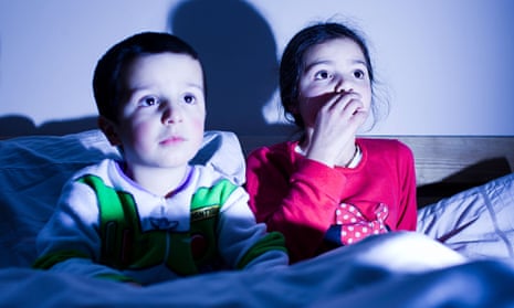 siblings watching TV in bed together