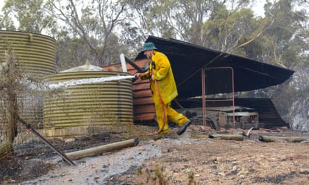 A Country Fire Service volunteer douses spot fires beside a burnt out shed near One Tree Hill in the Adelaide Hills.