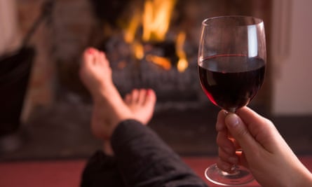 Woman drinking wine in  front of the fire.