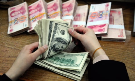 A Chinese bank worker counts a stack of US dollars together with stacks of 100 Chinese yuan notes at a bank in Hefei, east China's Anhui province on March 9, 2010.  China and the USA have pledged action to reduce the costs of climate change.