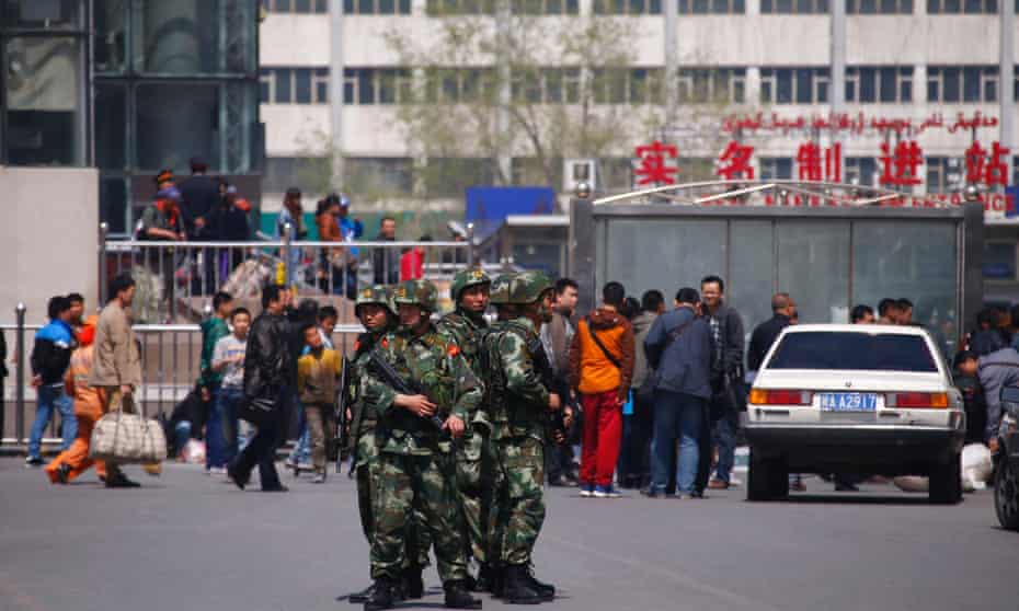 Paramilitary policemen stand guard near the exit of the South Railway Station, in Urumqi, Xinjiang. Authorities there say everyone buying a computer or mobile phone must now register personal details.