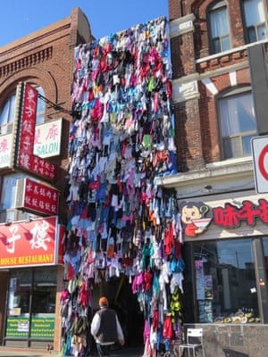 a storefront with t shirts hanging outside it reaching to the top of the buildings either side