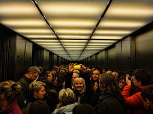 a photo of a group of people in a lift with the mirrors reflecting them