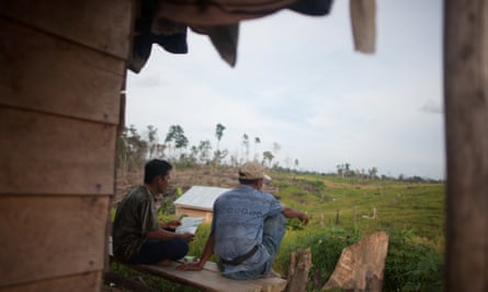 Two migrant farmers originally from Java sat by a house inside the Harapan Rainforest in Sumatra, Indonesia. Harapan is managed by a consortium of bird conservation groups, led by the RSPB. The project aims to restore an area of degraded forest close to the size of London.