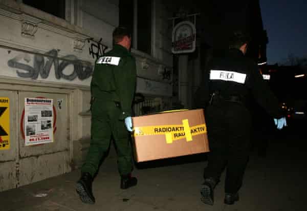 Two policeman carry a cardboard box, secured with tape marked radioactive from an apartment building in Hamburg-Ottensen
