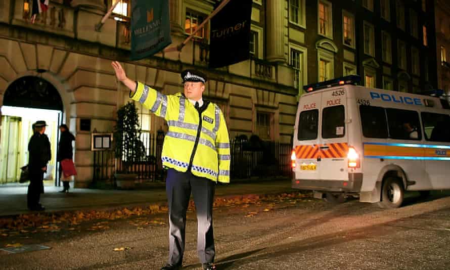 A British police officer blocks traffic as a police van takes up a position outside the Millennium hotel in Grosvenor Square in London