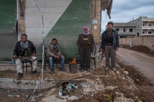 Kurdish fighters sit around a brazier while they keep guard over the deserted city