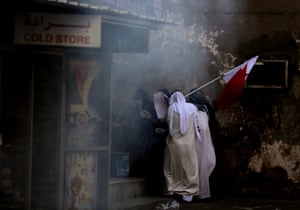 Manama, Bahrain Bahraini anti-government protesters holding a national flag take cover from tear gas during clashes