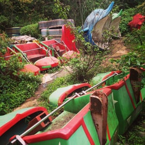 Shells of dolphin rides poke through vines, and a disused rollercoaster lays on its side at an abandoned amusement park in Nyarutarama, an area of Kigali, Rwanda. 